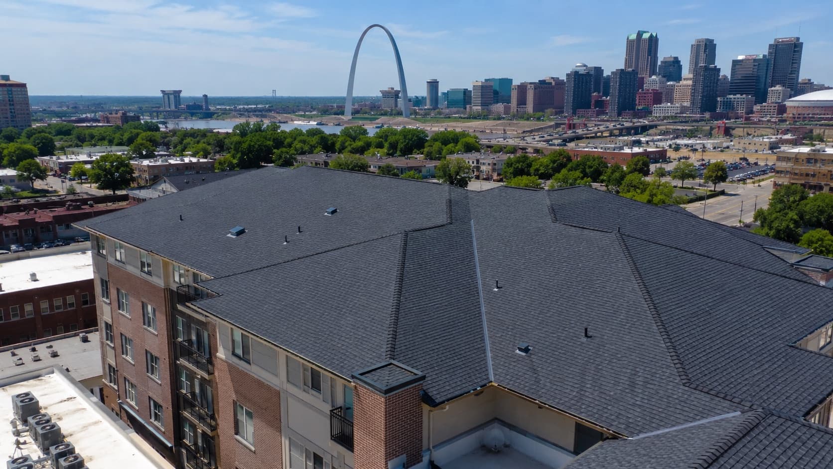 Aerial view of a completed roofing project over the St. Louis skyline